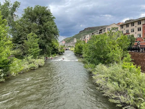 Clear Creek east of the Washington Avenue bridge in Golden, kayakers in the current and North Table Mountain behind the town