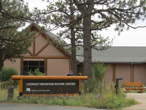 The log-framed Lookout Mountain Nature Center sign in front of the centre's stucco-and-timber building among ponderosa pines