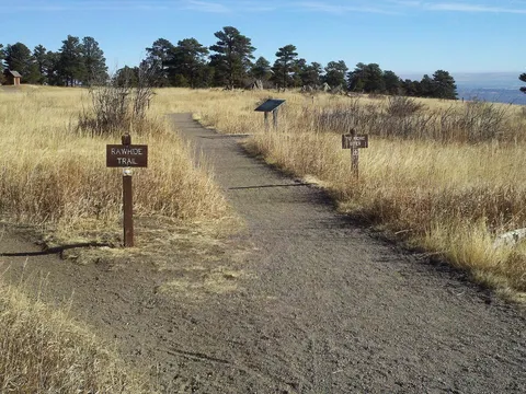The Rawhide Trail leaving the West Trailhead of White Ranch Park on Belcher Hill Road, a gravel path through winter grass and ponderosa pines with its trail sign, December 2010